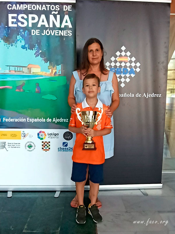 niño ajedrecista con su madre muestra trofeo